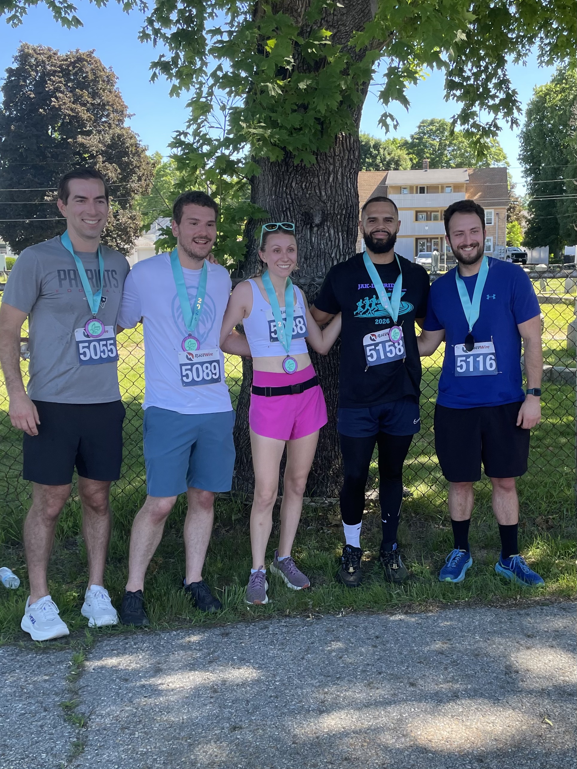 Five runners with medals posing together